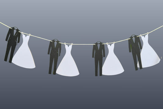 picture of wedding dresses and suits hanging on a line against a gray background